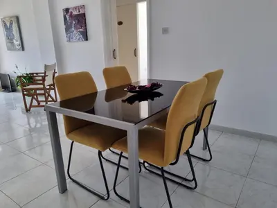 a dining room table and chairs with a black table and yellow chairs at Ikaros Boutique Apartment in Limassol