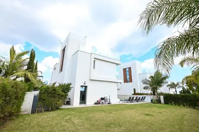 a white house with palm trees in front of it at By the Beach Villa 12 in Protaras
