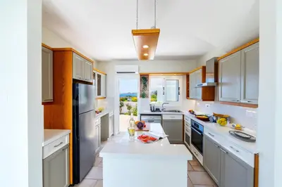 a large kitchen with white counters and cabinets at Protaras Seafront Villa Violetta in Protaras