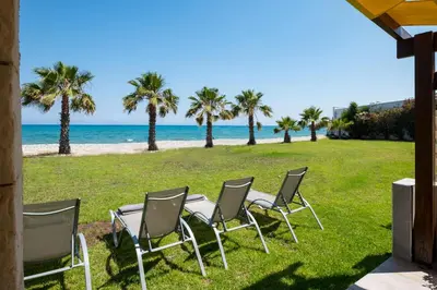 a group of chairs sitting on the grass near the beach at Pebble Beach Apartment in Voroklini