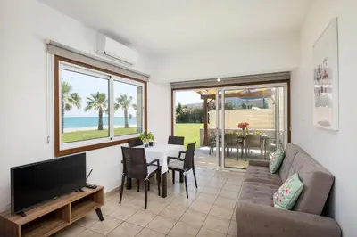 a living room with a couch and a tv and a table at Pebble Beach Apartment in Voroklini
