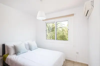 a white bedroom with a bed and a window at Oceanview Apartment in Larnaka