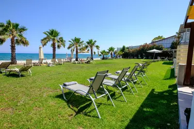 a row of chairs sitting on the grass near the beach at Oceanview Apartment in Larnaka