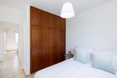 a bedroom with a white bed with a wooden headboard at Oceanview Apartment in Larnaka