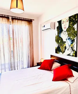 a bedroom with a bed with two red pillows at BALI SUITES 101 in Larnaka