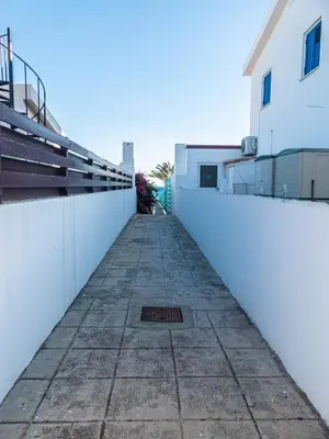 a sidewalk in front of a white wall at Greek Island Style 2 bedroom Villa with Pool next to the Sea in Larnaka