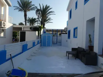 a patio with blue and white buildings and palm trees at Greek Island Style 2 bedroom Villa with Pool next to the Sea in Larnaka
