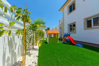 a yard with a playground and a house at Villa Lantos Central Protaras in Protaras