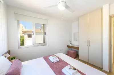 a white bedroom with a bed and a window at Villa Lantos Central Protaras in Protaras