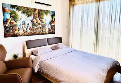a bedroom with a bed and a chair and a painting at BALI SUITES 505 in Larnaka