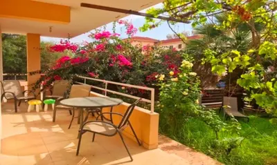 a patio with a table and chairs and flowers at 2 bedroom with private garden, walk to Nissi Beach, communal swimming pool in Ayia Napa