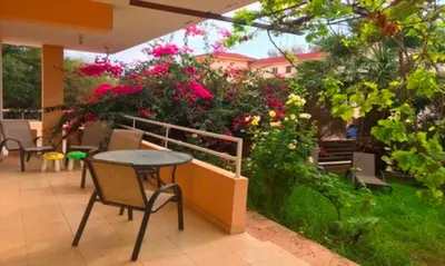 a patio with a table and chairs and flowers at 2 bedroom with private garden, walk to Nissi Beach, communal swimming pool in Ayia Napa