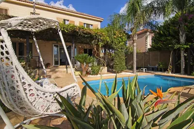 a white rocking chair in front of a swimming pool at Villa Polina in Ayia Napa