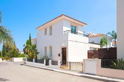 a white house with a fence and palm trees at Villa Danata in Protaras