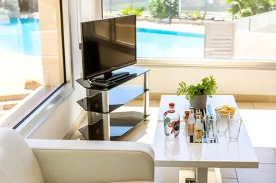 a living room with a tv and a table with a television at Fig Tree bay Apartment 103 in Protaras