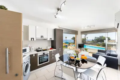a kitchen and living room with a table and chairs at Fig Tree bay Apartment 103 in Protaras