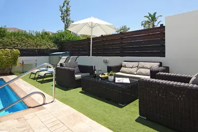 a patio with wicker furniture next to a swimming pool at Villa Palm in Protaras