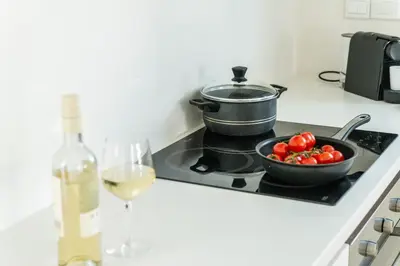 a pot on a stove with a bowl of tomatoes and a glass of wine at Protaras Villa Dafni in Protaras