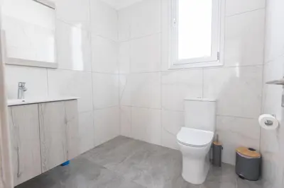 a white bathroom with a toilet and a sink at Sol E Mar Villas ( Gold Emerging Villas ) in Protaras