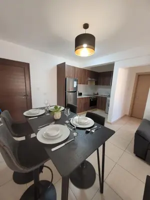 a dining room with a black table and a kitchen at Cielo Apartment in Ayia Napa