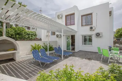 a white house with a patio with chairs and a table at Merab Holidays Apartment Castalia 62 in Ayia Napa