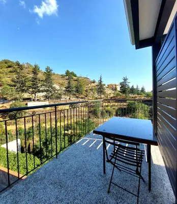 a table and a chair on a balcony with a view at Agros Green Valley Suites in Limassol