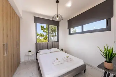 a bedroom with a white bed and a window at Alasia Villas in Paralimni