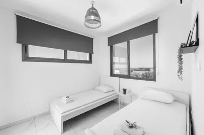 a white bedroom with a bed and a bench at Alasia Villas in Paralimni