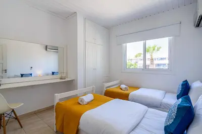 a white bedroom with two beds and a window at Keylana's 2-BR Apt in Pyla in Pyla