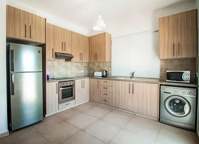 a kitchen with wooden cabinets and a stainless steel refrigerator at Nissi Villa Ourania in Ayia Napa