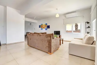 a living room with a couch and a tv at Nissi Villa Ourania in Ayia Napa