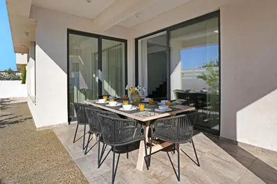 a dining room table with chairs on a patio at Villa Queen Valentina in Protaras