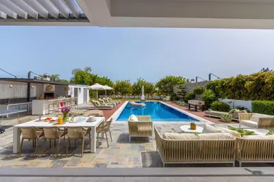 a patio with a table and chairs next to a pool at Green Heaven Villa 3 in Protaras