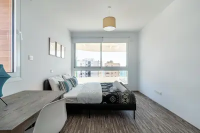 a bedroom with a bed and a table and a window at Oyster 1-BR Apt in Larnaca in Larnaka
