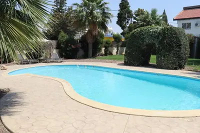 a swimming pool with blue water in a yard at Mediterranean poolside garden cottage in Kiti