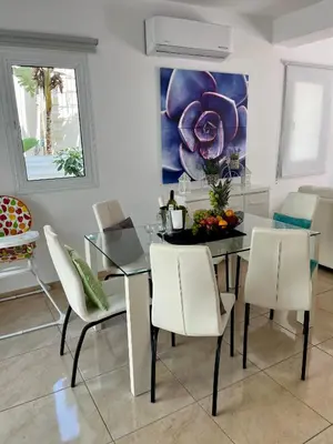 a dining room with a glass table and white chairs at Villa Katia in Protaras