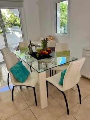 a dining room with a glass table and white chairs at Villa Katia in Protaras