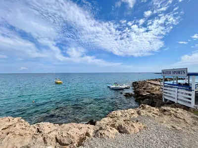 two boats in the water near a rocky shore at Villa Katia in Protaras