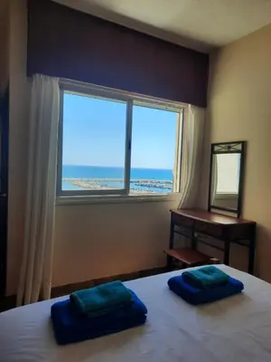 a bedroom with a bed with a window and a desk at Seascape 501 in Larnaka