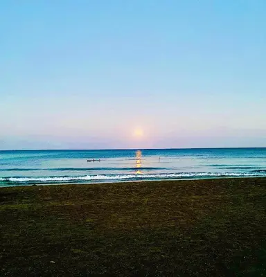 a beach with the sun rising over the ocean at BALI SUITES 202 in Larnaka
