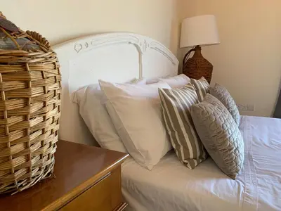 a bed with white pillows and a basket on it at Villa Grand Zeus in Anoyira