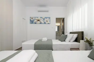 a white room with two beds and a couch at Villa Queen Eleanor in Protaras