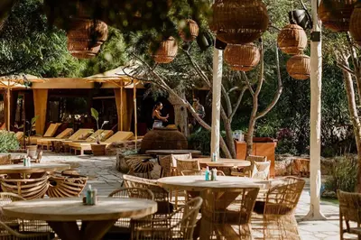 a patio with tables and chairs and a woman in the background at Villa Queen Helena in Protaras