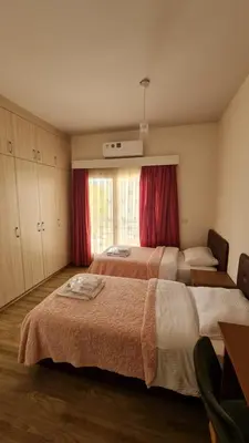 a bedroom with two beds and a window with red curtains at Oytam apt in Nicosia