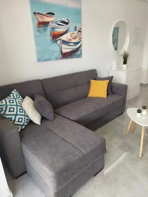 a living room with a couch and a painting of boats at Amazing Napa Apartment in Ayia Napa