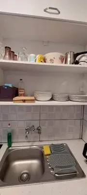 a kitchen sink with plates and dishes on a shelf at Stay With Oleg C17 in Paralimni