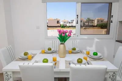 a dining room table with a vase of flowers on it at Villa suncity Boutique Beachfront in Ayia Napa