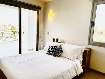 a bedroom with a bed with white sheets and a window at The Penthouse 401 in Larnaka