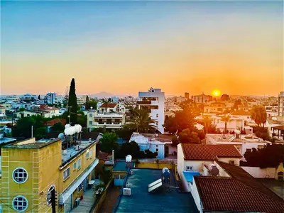 a cityscape of a city with the sun setting at The Penthouse 401 in Larnaka