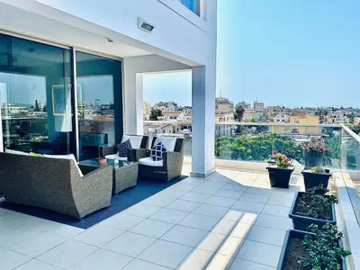 a balcony with chairs and tables on a building at The Penthouse 401 in Larnaka